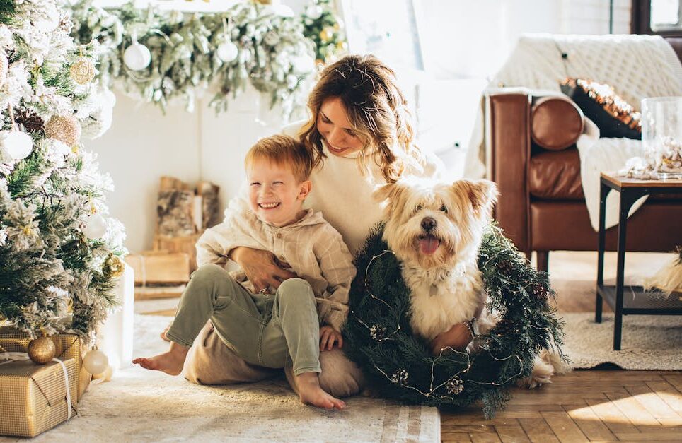 Mother, child, and dog enjoying Christmas morning by the decorated tree at home.